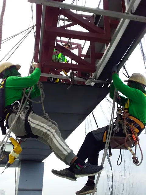 Technicians on ropes working on a steel frame structure